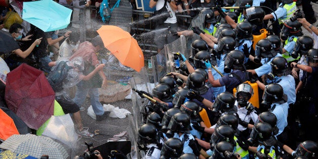 Riot police use pepper spray against protesters after thousands of people block a main road to the financial central district outside the government headquarters in Hong Kong, Sunday, Sept. 28, 2014. A tense standoff between thousands of Hong Kong pro-democracy protesters and police warning of a crackdown spiraled into an extraordinary scene of chaos Sunday as the crowd jammed a busy road and clashed with officers wielding pepper spray. (AP Photo/Vincent Yu)