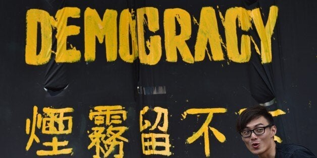 A pro-democracy protester stands next to a banner in Hong Kong on September 30, 2014. China on September 30 called major pro-democracy demonstrations in Hong Kong 'illegal', as state media insisted Beijing would not give in but would wait for public opinion to turn against the protests. AFP PHOTO / Philippe Lopez (Photo credit should read PHILIPPE LOPEZ/AFP/Getty Images)