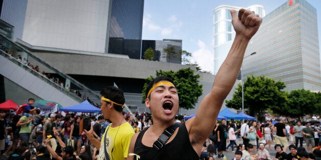 A pro-democracy activist shouts slogans on a street near the government headquarters where protesters have made camp, Wednesday, Oct. 1, 2014 in Hong Kong. Holiday crowds swelled into the tens of thousands as student leaders met with other pro-democracy protesters Wednesday to thrash out a strategy for handling the government's rejection of their demands that the city's top leader resign and Beijing revise its plans to limit political reforms. (AP Photo/Wong Maye-E)