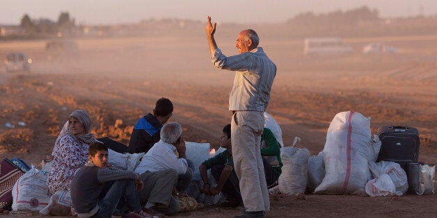 SANLIURFA, TURKEY - OCTOBER 01: Refugees sit with their belongings after crossing the border from Syria into Turkey on October 1 , 2014 near Suruc, Turkey. Kurdish troops are engaged in a battle against fighters of the Islamic State (IS, also called ISIS and ISIL) to defend the strategic nearby Kurdish border town of Kobani (also called Ayn Al-Arab), which ISIS has surrounded on three sides. The Turkish Parliament is due to vote on a measure on October 2, which would allow Turkish ground forces to enter Syria, creating a buffer zone to protect fleeing refugees from the ISIS advance. (Photo by Carsten Koall/Getty Images)