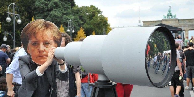 BERLIN, GERMANY - AUGUST 30: A woman holding a mock telescope and wearing a mask showing German Chancellor Merkel attends the demonstration 'Liberty instead of Fear' in front of Brandenburg Gate in the capital Berlin, Germany on August 30, 2014. (Photo by Erbil Basay/Anadolu Agency/Getty Images)