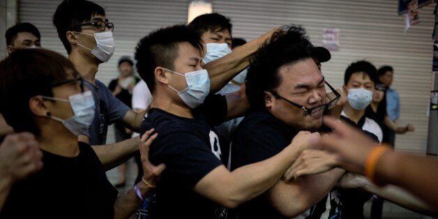A group of men in masks beat up a man (R) who tried to stop them from removing barricades from a pro-democracy protest area in the Causeway Bay district of Hong Kong on October 3, 2014. Hong Kong has been plunged into the worst political crisis since its 1997 handover as pro-democracy activists take over the streets following China's refusal to grant citizens full universal suffrage. AFP PHOTO / ALEX OGLE (Photo credit should read Alex Ogle/AFP/Getty Images)