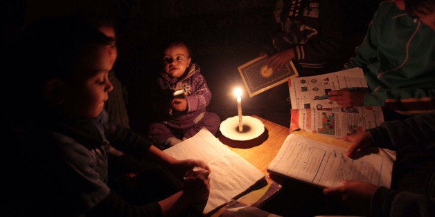 GAZA CITY, GAZA - MARCH 15: Palestinian children sit inside thier makeshift house during power cuts in Khan Younis in the southern Gaza Strip on March 15, 2014. The Gaza Strip's sole power station stopped generating electricity on Saturday, after consuming the last drop of fuel following Israel's closure of the Karam Abu Salem crossing, Gaza's energy authority said. Last Wednesday, the Israeli army declared a series of sanctions against Gaza in the wake of the firing of a rocket salvo into the self-proclaimed Jewish state. The sanctions include the closure of all border crossings with Gaza as well as suspending the entry of commercial goods. (Photo by Ashraf Amra/Anadolu Agency/Getyy Images)