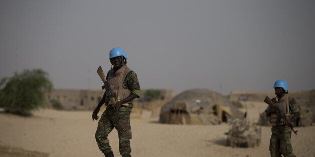 United Nations peacekeepers from Burkina Faso walk through a neighborhood on the outskirts of Timbuktu, Mali, during a patrol, Tuesday, July 23, 2013. Mali's presidential election is set to go ahead on Sunday despite massive logistical and technical lapses, including a voters' roll which inexplicably is missing the names of tens of thousands of registered voters.(AP Photo/Rebecca Blackwell)