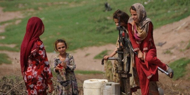 ISLAMABAD, PAKISTAN - SEPTEMBER 19: Slum dwelling children draw drinking water from a hand pump at a street as they lead life in poverty and unhealthy conditions in Islamabad, Pakistan, on September 19, 2014. Many slum dwellers consist of children and deprived of fundamental rights. According to news reports, children from at the ages of 7-8 start to work and they earn their livelihood for their families. (Photo by Muhammed Reza/Anadolu Agency/Getty Images)