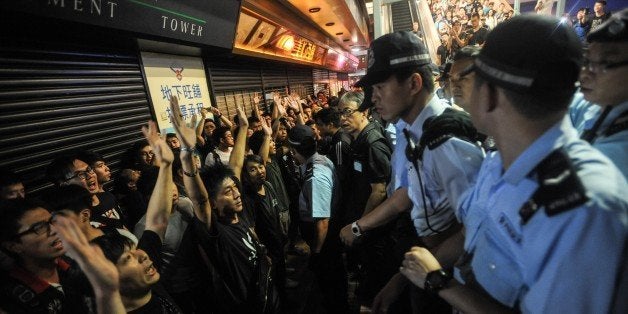 HONG KONG - OCTOBER 04: Pro-democracy protestors raise their hands as Hong Kong police officers take security measures in the Mong Kok area of Hong Kong, on October 4, 2014. Protesters continued to block main transport routes, after a peaceful night of demonstrations in the Chinese territory. The protests followed a decision last month by China's top legislative body to restrict the nominations for chief executive in 2017. The candidate who wins the popular vote would have to be formally appointed by the central government before taking office. (Photo by Thomas Campean/Anadolu Agency/Getty Images)