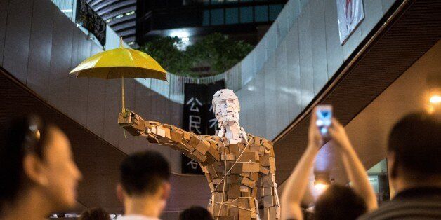 The statue 'Umbrella Man' by the Hong Kong artist known as Milk, is set up at a pro-democracy protest site next to the central government offices in Hong Kong on October 5, 2014. Pro-democracy demonstrators stood divided Sunday over whether to withdraw from protest sites across Hong Kong, hours before a government deadline to clear key roads they have blockaded for the last week. Embattled Chief Executive Leung Chun-ying has said his administration was determined to 'take all necessary actions to restore social order' and pave the way for government staff to resume work by Monday morning. AFP PHOTO / ALEX OGLE RESTRICTED TO EDITORIAL USE, MANDATORY CREDIT OF THE ARTIST, TO ILLUSTRATE THE EVENT AS SPECIFIED IN THE CAPTION (Photo credit should read Alex Ogle/AFP/Getty Images)