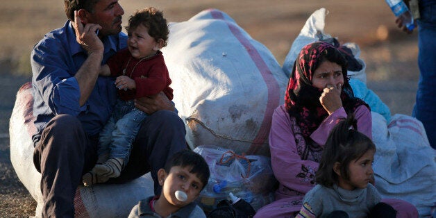 Kurdish refugees wait by the side of the road near Suruc, Turkey, after their arrival from Kobani, as fighting intensified between Syrian Kurds and the militants of Islamic State group, Sunday, Oct. 5, 2014. Kobani, also known as Ayn Arab, just a few hundred meters inside Syria and its surrounding areas have been under attack since mid-September, with militants capturing dozens of nearby Kurdish villages. (AP Photo/Lefteris Pitarakis)