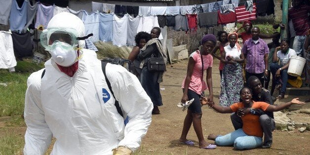 People look on as a woman reacts after her husband is suspected of dying from the Ebola virus, in the Liberian capital Monrov