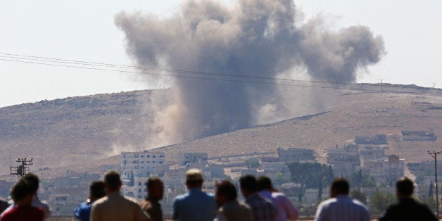 SANLIURFA, TURKEY - OCTOBER 08: A photograph taken from Suruc district of Sanliurfa, Turkey, shows that local residents watch smoke rising from the Syrian border town of Kobani (Ayn al-Arab) following the US-led coalition airstrikes against the Islamic State of Iraq and the Levant (ISIL) on October 8, 2014. (Photo by Emin Menguarslan/Anadolu Agency/Getty Images)