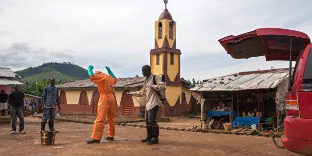 A volunteer in protective suit is being sprayed with disinfectant by another volunteer in Waterloo, some 30 kilometers southeast of Freetown, on October 7, 2014, after carrying bodies of people who died of Ebola. Dozens of British military personnel are due to fly to Sierra Leone next week to help build medical facilities to combat the Ebola epidemic, the defence ministry said on October 7. AFP PHOTO / FLORIAN PLAUCHEUR (Photo credit should read FLORIAN PLAUCHEUR/AFP/Getty Images)