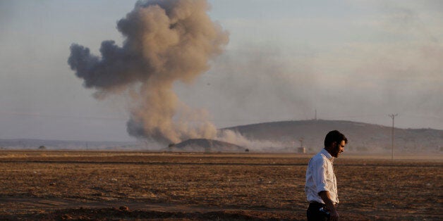 A Turkish Kurd walks away as airstrikes hit Kobani, inside Syria, as fighting intensifies between Syrian Kurds and the militants of Islamic State group, in Mursitpinar, on the outskirts of Suruc, at the Turkey-Syria border, Wednesday, Oct. 8, 2014. Kobani, also known as Ayn Arab and its surrounding areas have been under attack since mid-September, with militants capturing dozens of nearby Kurdish villages. (AP Photo/Lefteris Pitarakis)