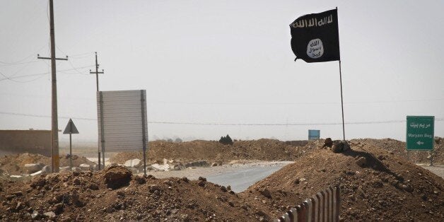 A flag of the Islamic State (IS) is seen on the other side of a bridge at the frontline of fighting between Kurdish Peshmerga fighters and Islamist militants in Rashad, on the road between Kirkuk and Tikrit, on September 11, 2014. Ten Arab states, including heavyweight Saudi Arabia, agreed today in Jeddah to rally behind Washington in the fight against Islamic State jihadists, as it seeks to build an international coalition. AFP PHOTO/JM LOPEZ (Photo credit should read JM LOPEZ/AFP/Getty Images)