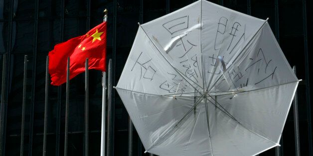 An umbrella is displayed on a fence next to a Chinese flag at the government headquarters in Hong Kong's Admiralty, Friday, Oct. 10, 2014. A pro-democracy protest that has blocked main roads in Hong Kong for almost two weeks could drag on for days yet, after talks aimed at resolving a bitter standoff between the city's government and student demonstrators collapsed Thursday. The slogan on the umbrella reads: "Are you isolated from the world?" (AP Photo/Kin Cheung)