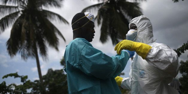 MONROVIA, LIBERIA - OCTOBER 10: An Ebola burial team dresses in protective clothing before collecting the body of a woman, 54, from her home in the New Kru Town suburb on October 10, 2014 of Monrovia, Liberia. The World Health Organization says the Ebola epidemic has now killed more than 4,000 people in West Africa. (Photo by John Moore/Getty Images)