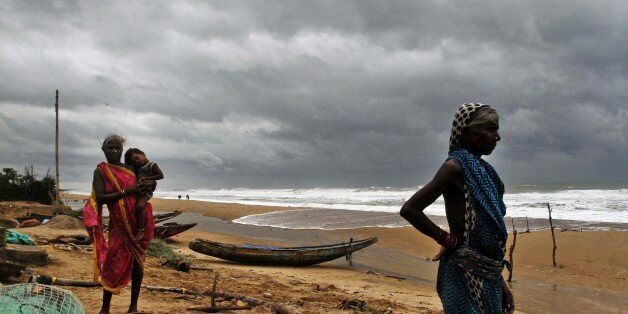 Fisherwomen watch the sea waves before evacuating the place near Podampeta village, on the outskirts of Gopalpur beach in Ganjam district, 140 kilometers (87 miles) south of Bhubaneswar, India, Saturday, Oct. 11, 2014. Indian authorities were evacuating hundreds of thousands of people Saturday as a powerful cyclone âHudhudâ swept through the Bay of Bengal and headed toward the country's east coast. (AP Photo/Biswaranjan Rout)