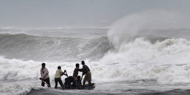 Indian fishermen negotiate their skiff through rough waves ahead of Cyclone Hudhud making expected landfall in Visakhapatnam on October 11, 2014. India on October 11 began evacuating thousands of people from fishing villages as it braced for Cyclone Hudhud barrelling towards its east coast, officials said. AFP PHOTO/STR (Photo credit should read STRDEL/AFP/Getty Images)