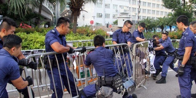 Police officers remove barricades from pro-democracy demonstrators (unseen) near the government offices in Hong Kong on October 13, 2014. Dozens of Hong Kong police were massing at protest sites where pro-democracy demonstrators have been holding more than two weeks of rallies, paralysing parts of the Asian financial hub. AFP PHOTO / Laurent FIEVET (Photo credit should read LAURENT FIEVET/AFP/Getty Images)