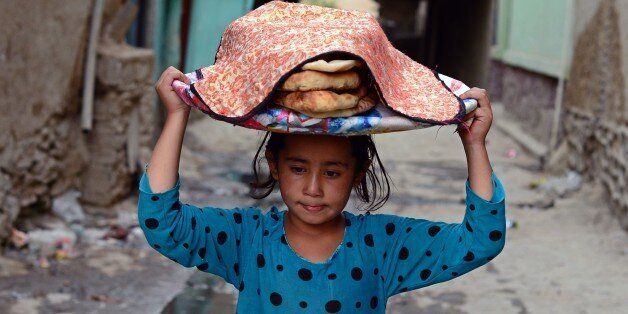 An Afghan child carries a basket of bread on her head in the old section of Kabul on September 2, 2014. Afghanistan's economy has improved significantly since the fall of the Taliban regime in 2001 largely because of the infusion of international assistance. Despite significant improvement in the last decade the country is still extremely poor and remains highly dependent on foreign aid. AFP PHOTO/Wakil Kohsar (Photo credit should read WAKIL KOHSAR/AFP/Getty Images)