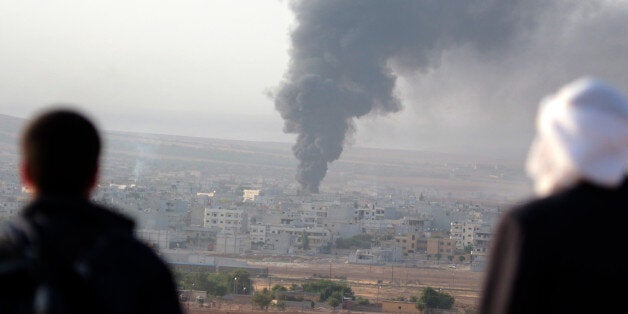 SANLIURFA, TURKEY - OCTOBER 13: People are seen as black smoke rising after US-led coalition's air forces airstrikes against Islamic State of Iraq and Levant (ISIL) members in Ayn al-Arab of northern Syria, in Suruc district of Turkey's Sanliurfa on October 13, 2014. (Photo by Omer Urer/Anadolu Agency/Getty Images)