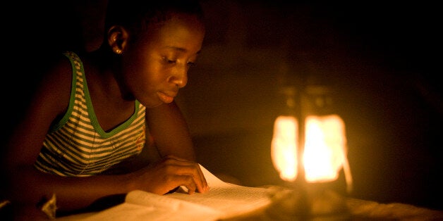 NEAR ACCRA, GHANA - 2009/02/19: Rural Ghanian students study with the help of a kerosene lantern in the evening. Many village
