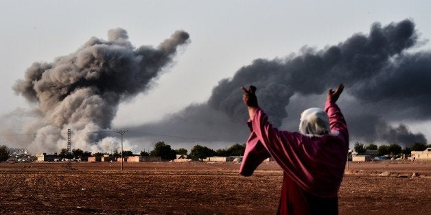 A woman reacts as smoke rises from the the Syrian town of Ain al-Arab, known as Kobane by the Kurds, after a strike from the US-led coalition as it seen from the Turkish - Syrian border in the southeastern village of Mursitpinar, Sanliurfa province, on October 13, 2014. AFP PHOTO / ARIS MESSINIS (Photo credit should read ARIS MESSINIS/AFP/Getty Images)