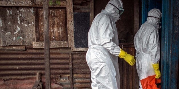 MONROVIA, LIBERIA - OCTOBER 14: Red cross health workers who wear protective gear, prepare to move the body of 67-year-old Jenneh Momoh died due to Ebola virus in Caldwell town of Monrovia, Liberia on 14 October, 2014. (Photo by Mohammed Elshamy/Anadolu Agency/Getty Images)