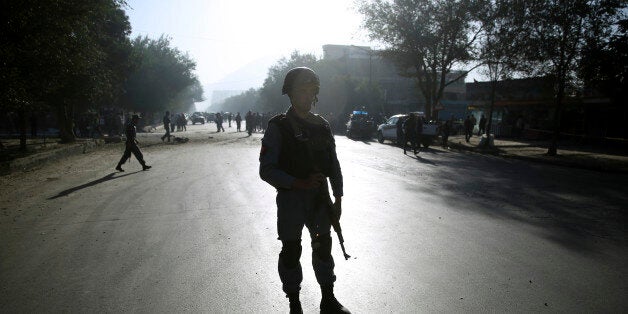 An Afghan security soldier stands guard at the site of a suicide attack in Kabul, Afghanistan, Wednesday, Oct. 1, 2014. Two suicide bombers in the Afghan capital targeted two buses carrying Afghan army troops on Wednesday, killing several people and wounding over a dozen others, police said. (AP Photo/Massoud Hossaini)