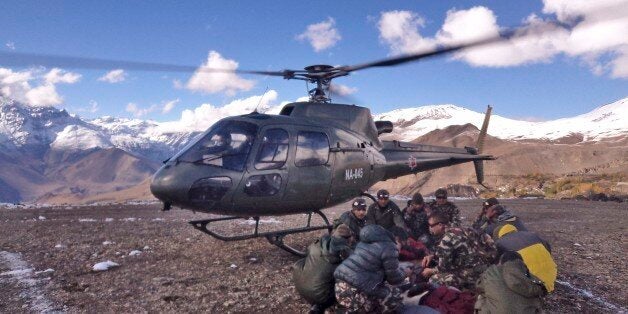 In this photo provided by the Nepalese army, soldiers prepare to airlift an avalanche victim in Thorong La pass area, Nepal, Wednesday, Oct. 15, 2014. An avalanche and blizzard in Nepal's mountainous north have killed at least 12 people, including eight foreign trekkers, officials said Wednesday. Five other climbers were hit by a separate avalanche on Mount Dhaulagiri and remain missing. (AP Photo/Nepalese Army)