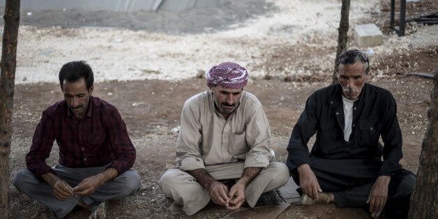 SANLIURFA, TURKEY - OCTOBER 14: Syrian Kurdish men, fled from clashes between the Islamic State of Iraq and Levant (ISIL) militants and pro-Kurdish Democratic Union Party (PYD) forces in Ayn al-Arab city (Kobani) with a group, rest outside of a tent at the refugee camp in Turkey's Syrian border district of Suruc of Sanliurfa on October 14, 2014. (Photo by Murat Kula/Anadolu Agency/Getty Images)