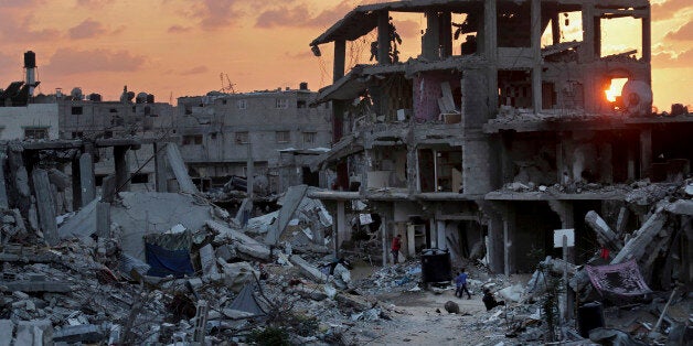 Palestinians walk during the sunset between the rubble of their destroyed building in Shijaiyah neighborhood of Gaza City in