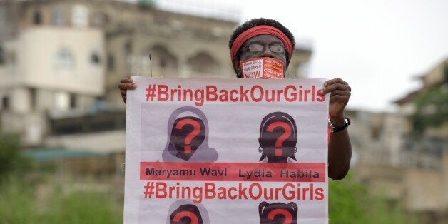 A supporter of the #BringBackOurGirls campaign carries a placard showing the missing faces of the kidnapped Chibok schoolgirl during a demonstration in the Nigerian capital Abuja on October 14, 2014. Nigerian police on Tuesday blocked supporters of 219 schoolgirls kidnapped by Boko Haram militants from marching on the president's official residence on the six-month anniversary of the abduction. A wall of female officers in full riot gear formed the first line of a barricade in front of less than 100 members of the Bring Back Our Girls campaign, preventing them from setting out.AFP PHOTO/PIUS UTOMI EKPEI (Photo credit should read PIUS UTOMI EKPEI/AFP/Getty Images)