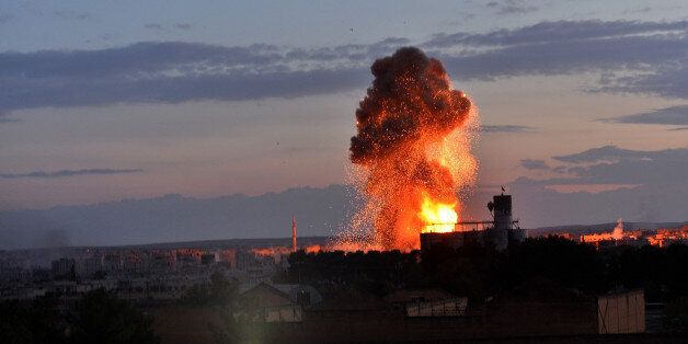 GAZIANTEP, TURKEY - OCTOBER 18: A photograph taken from Suruc district of Sanliurfa, Turkey, shows flames and smoke rising from an explosion in the Syrian border town of Kobani (Ayn al-Arab) following a US-led coalition airstrike hits an Islamic State of Iraq and the Levant (ISIL) target on October 18, 2014. (Photo by Omer Urer/Anadolu Agency/Getty Images)