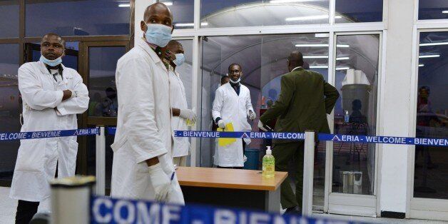 Medical staff, wearing protective masks, wait for passengers arriving from Conakry in Guinea at the airport in Abidjan on October 20, 2014 as Ivory Coast's airline resumed flights to the three west African countries worst-hit by Ebola -- Guinea, Liberia and Sierra Leone. The worst-ever outbreak of the deadly virus has killed more than 4,500 people, almost all in west Africa, with close to 2,500 deaths registered in Liberia alone. AFP PHOTO / ISSOUF SANOGO (Photo credit should read ISSOUF SANOGO/AFP/Getty Images)