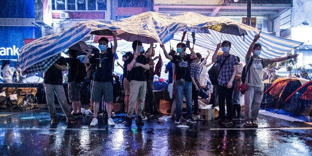 HONG KONG - OCTOBER 22: Protesters shelter from the rain under umbrella at the occupation zone at Mongkok on October 22, 2014 in Hong Kong. Police have begun to take measures to remove the blockades put in place by pro-democracy supporters, as protests entered a fourth week. (Photo by Lam Yik Fei/Getty Images)