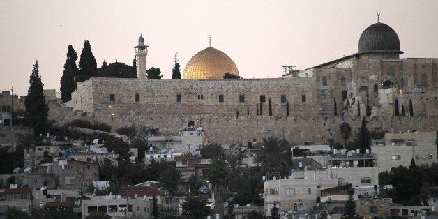 A picture taken on October 21, 2014 shows the Dome of the Rock in the Al-Aqsa mosque compound behind the east Jerusalem neighborhood of Silwan, a densely-populated Palestinian neighbourhood on a steep hillside flanking the southern walls of Jerusalem's Old City. By fair means or foul, Jewish settlers are notching up property gains in the heart of Arab east Jerusalem through a series of shady deals involving local frontmen or straw companies. Over the past three weeks, hardline settlers have moved into 35 apartments in the area, sparking anger and consternation among local Palestinians, who vehemently oppose such moves as a hostile attempt to Judaise the area. AFP PHOTO/AHMAD GHARABLI (Photo credit should read AHMAD GHARABLI/AFP/Getty Images)