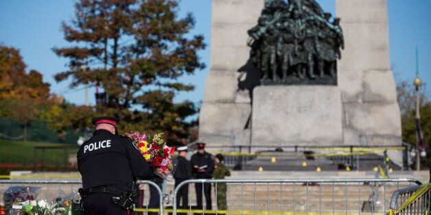 OTTAWA, ON - OCTOBER 23: An Ottawa police officer lays flowers and pays his respects for Cpl. Nathan Cirillo of the Canadian Army Reserves at the National War Memorial, who was killed yesterday while standing guard at the memorial, on October 23, 2014 in Ottawa, Canada. After killing Cirillo the gunman stormed the main parliament building, terrorizing the public and politicians, before he was shot dead. (Photo by Andrew Burton/Getty Images)
