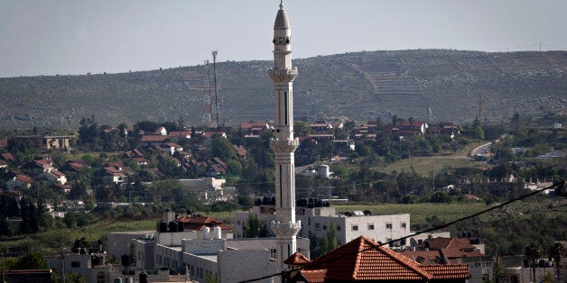 In this April 17, 2014 photo, the minaret of the main mosque of the Palestinian village of Silwad overlooks the adjacent Israeli settlement of Ofra, in the background, north of the West Bank city of Ramallah. (AP Photo/Nasser Nasser)