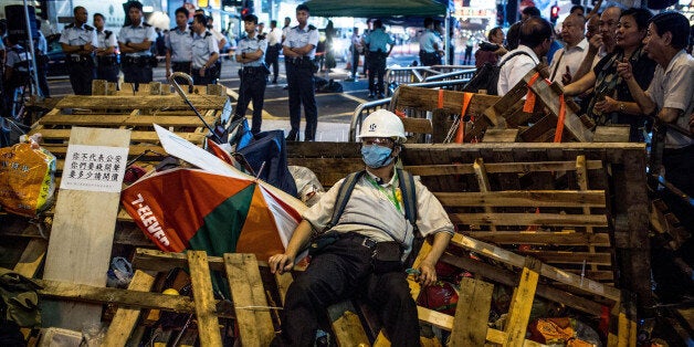 HONG KONG - OCTOBER 24: A pro-democracy protester guards a barricade from pro-China supporters on a street in Mong Kok on O