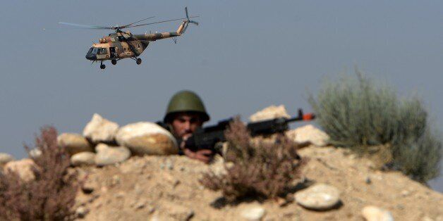 An Afghan National Army (ANA) soldier is seen at his position while an Afghan Air Force Mi-17 flies past during a combat training exercise at the Afghan National Military training centre (KMTC) in Kabul on October 22, 2014. Afghan casualties have rocketed over the past two years, during which time NATO has handed over most combat duties to the nation's police and army. The US military estimated this month that 7,000-9,000 Afghan police or troops had been killed or wounded so far this year. AFP PHOTO/Wakil Kohsar (Photo credit should read WAKIL KOHSAR/AFP/Getty Images)