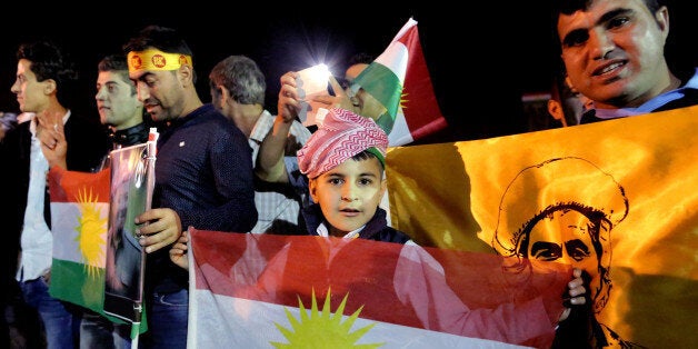 In this Tuesday, Oct. 28, 2014 photo, supporters of Kurdish Peshmerga forces hold a Kurdish flags as they wait for the troops to cross the border into Turkey en route to Kobani, at the Ibrahim Khalil border crossing in the Northern Kurdish Region of Iraq. A group of Iraqi Kurdish peshmerga troops arrived in Turkey early Wednesday, Oct. 29, on their way to Syria to help their Syrian Kurdish brethren fight Islamic State extremists in the embattled border town of Kobani. (AP Photo/Bram Janssen)