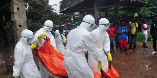 Health workers carry the body of a man suspected to have died of Ebola virus in Paynesville Community situated on the outskirts of Monrovia, Liberia, Tuesday, Oct. 21, 2014. Liberian President Ellen Johnson Sirleaf said Ebola has killed more than 2,000 people in her country and has brought it to "a standstill," noting that Liberia and two other badly hit countries were already weakened by years of war. (AP Photo/Abbas Dulleh)