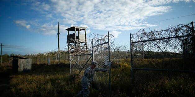 In this photo reviewed by the U.S. military, a soldier closes the gate at the now abandoned Camp X-Ray, which was used as the first detention facility for al-Qaida and Taliban militants who were captured after the Sept. 11 attacks at Guantanamo Bay Naval Base, Cuba, Thursday, Nov. 21, 2013. Detainees were housed in open air pens until the completion of Camp Delta in April 2002. (AP Photo/Charles Dharapak)