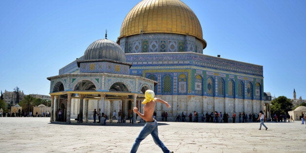 A Palestinian youth hurls stones at Israeli police officers, not seen, next to the Dome of the Rock Mosque in the Al Aqsa Mosque compound in Jerusalem's Old City, Friday, Sept. 6, 2013. Israeli police say several Palestinians threw rocks at officers and Jewish worshippers after Muslim prayers in Jerusalemâs Old City and 15 have been arrested. (AP Photo/Mahmoud Illean)