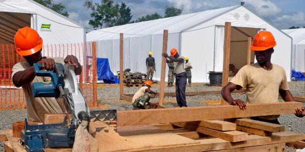 In this photo taken on Friday, Oct. 24, 2014, Liberian troops work to build a new section of an Ebola treatment center in the