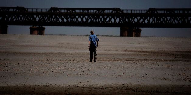 In this image taken on April 6, 2010, a man walks on a dried up bed of Pakistan's Chenab River, which originates from India, near Gujrat, Pakistan. A bitter dispute over limited water resources is fueling tensions between India and Pakistan at a time when the United States is trying to bring the two South Asian rivals together to focus on the war in Afghanistan. (AP Photo/B.K.Bangash)