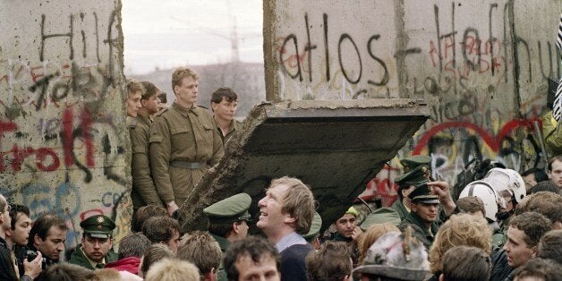 West Berliners crowd in front of the Berlin Wall early 11 November 1989 as they watch East German border guards demolishing a section of the wall in order to open a new crossing point between East and West Berlin, near the Potsdamer Square. Two days before, Gunter Schabowski, the East Berlin Communist party boss, declared that starting from midnight, East Germans would be free to leave the country, without permission, at any point along the border, including the crossing-points through the Wall in Berlin. The Berlin concrete wall was built by the East German government in August 1961 to seal off East Berlin from the part of the city occupied by the three main Western powers to prevent mass illegal immigration to the West. According to the 'August 13 Association' which specialises in the history of the Berlin Wall, at least 938 people - 255 in Berlin alone - died, shot by East German border guards, attempting to flee to West Berlin or West Germany. (Photo credit should read GERARD MALIE/AFP/Getty Images)