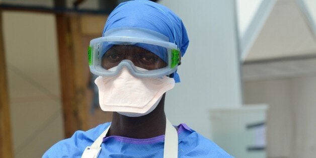 Health worker Mark Jerry, 36, stands on November 1, 2014 at the clinic run by the non-governmental organization Medecin Sans Frontieres (Doctors Without Border - MSF) in Monrovia. Jerry, who contracted the Ebola virus and got better, wears blue personal protective equipment (PPE), which is not completely protective, because he is now immune to the virus and can spend more time with infected patients. The virus has already infected more than 13,000 people in West Africa since the beginning of the year and killed more than 4,900 according to the World Health Organization. Ebola is spread through close contact with the bodily fluids of an infected person or a person who has recently died of the virus. AFP PHOTO / ZOOM DOSSO (Photo credit should read ZOOM DOSSO/AFP/Getty Images)