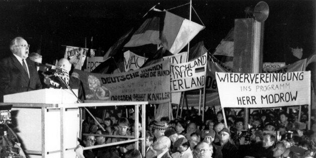 West German Chancellor Helmut Kohl gives a speech on the podium left, in front of the cathedral "Our Lady" in Dresden, East Germany, December 19, 1989. Banner right reads: Wiedervereinigung in Programm Herr Modrow (Reunification for your program Mr. Modrow). (AP Photo/Roberto Pfeil)