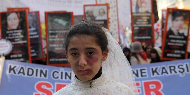 A Turkish girl, wearing a wedding dress and covered with fake bruises, stands in front of other protesters holding placard reading '' end violence'' during a demonstration to protest against rape, killings and domestic violence against women, in Ankara on November 27, 2011. AFP PHOTO/ADEM ALTAN (Photo credit should read ADEM ALTAN/AFP/Getty Images)